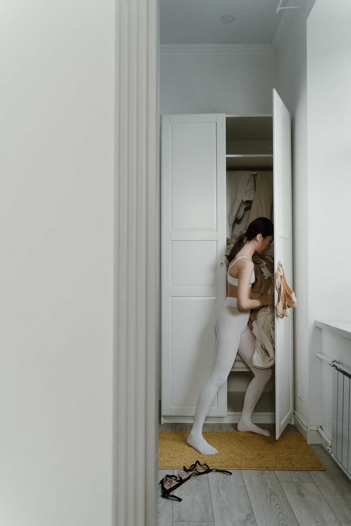 A woman sorting clothes in a wardrobe.