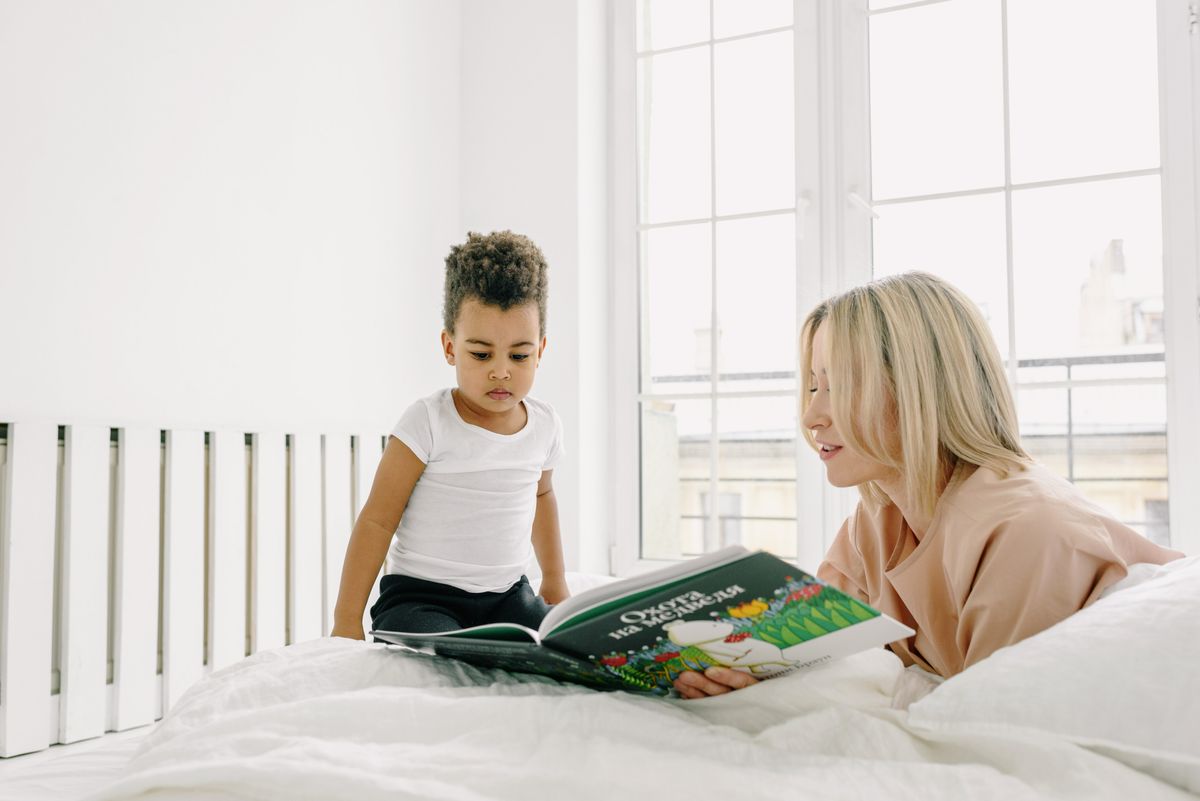 A woman and child reading together on a bed.