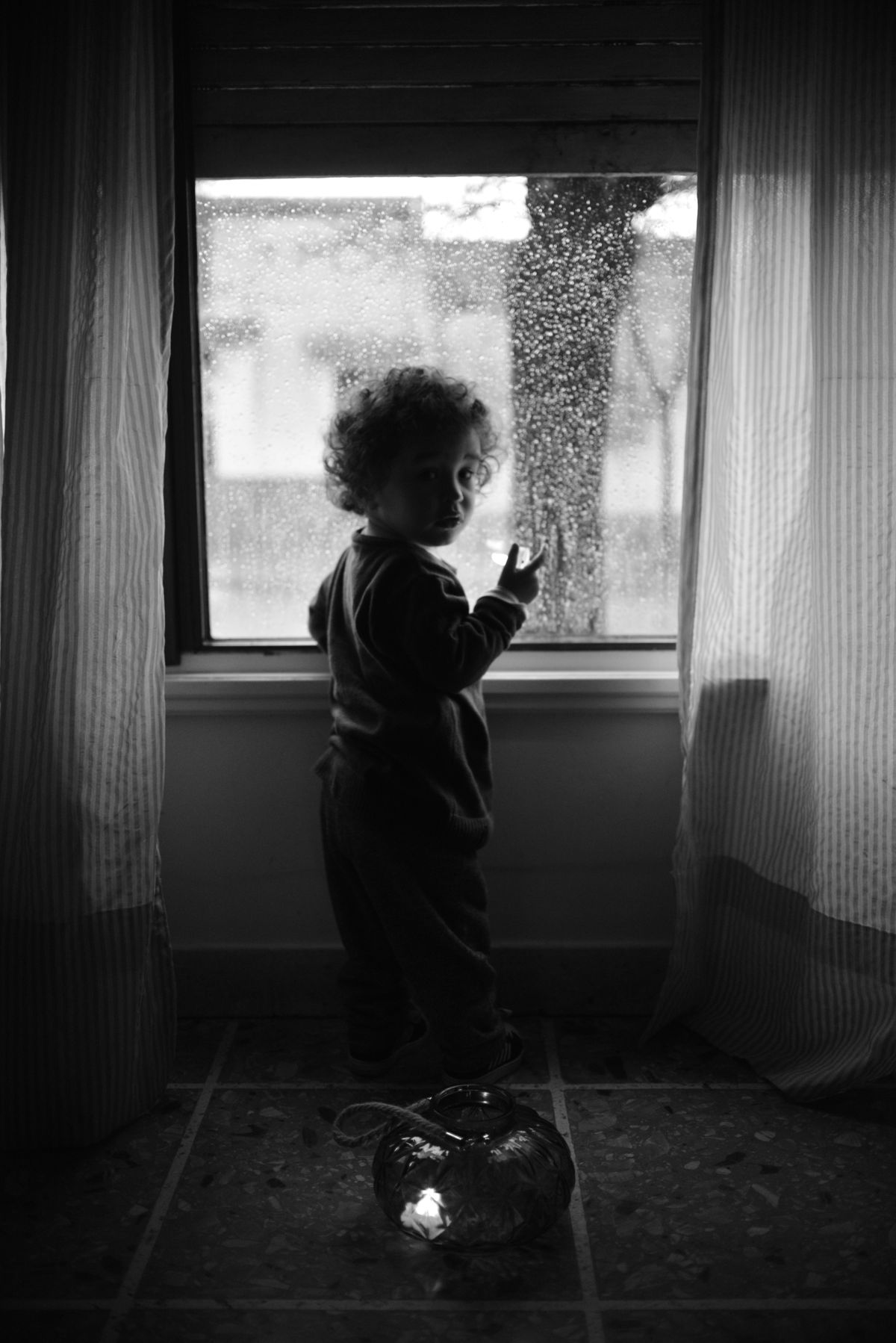 A child looking through a rain-covered window.