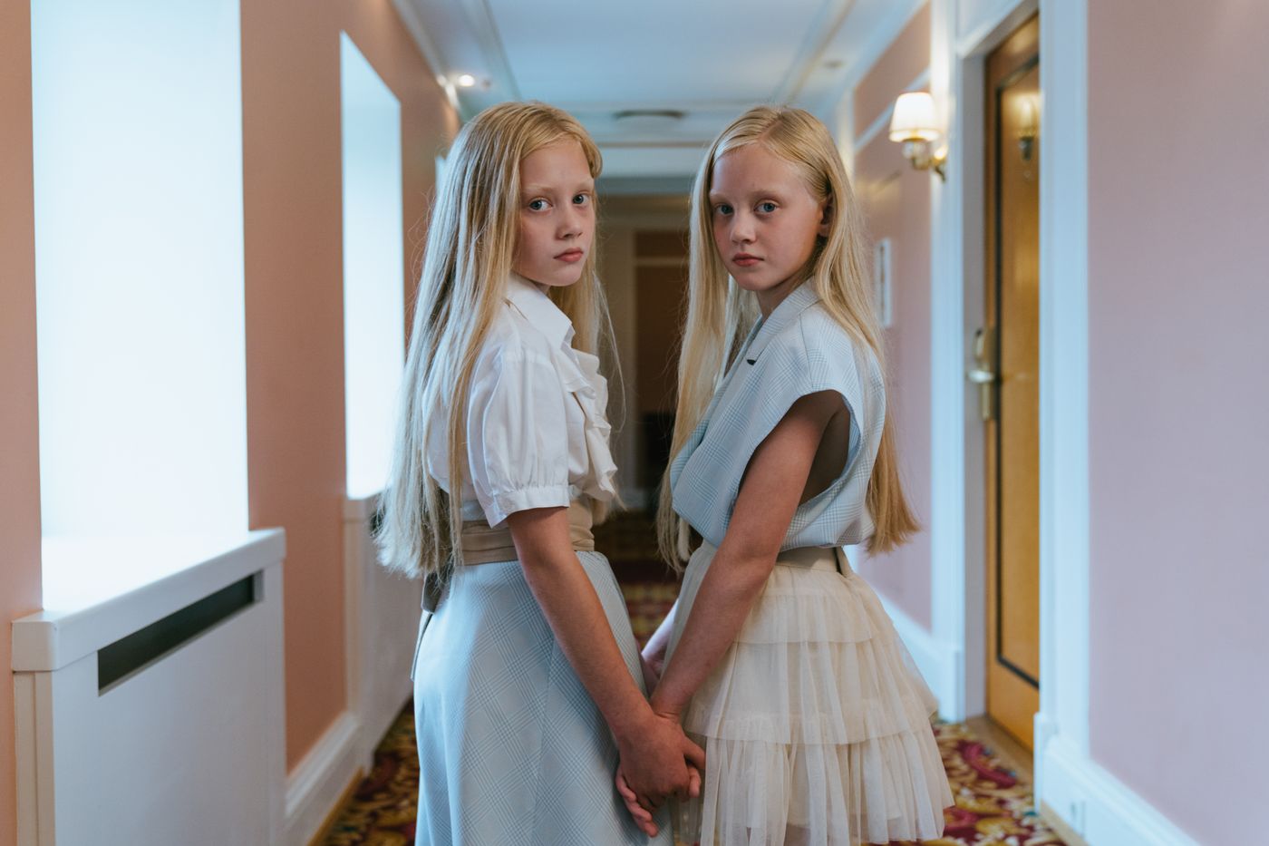 Two children holding hands in a hotel hallway