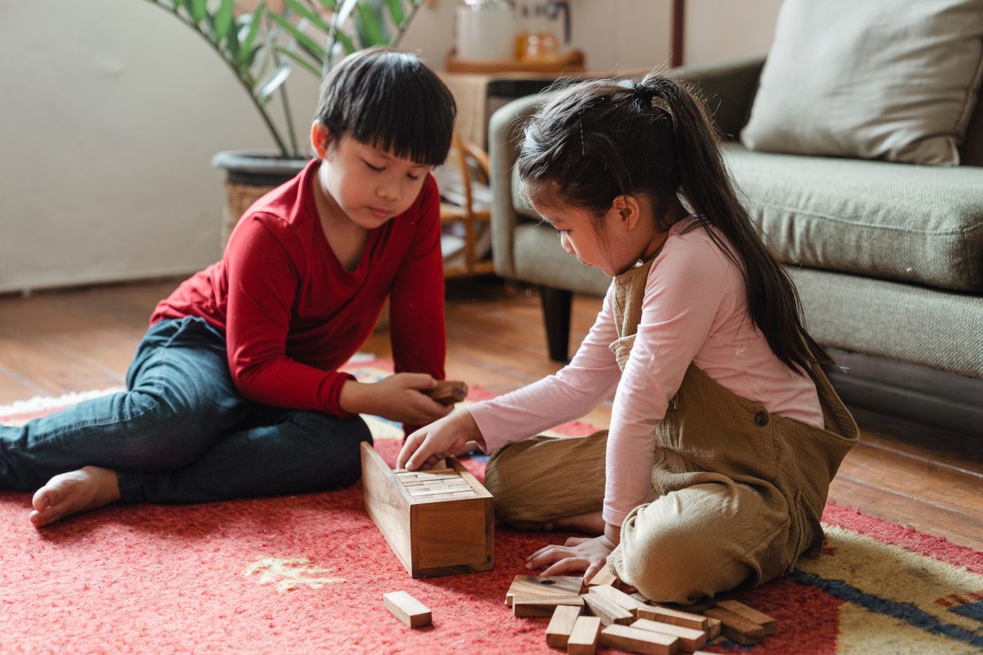 Two children playing with wooden blocks on a living room rug