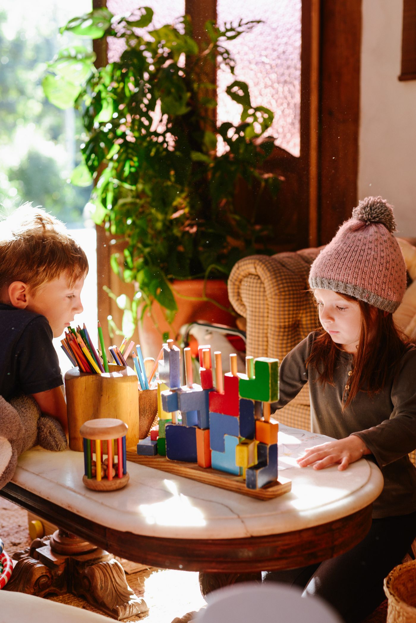 Two children playing with coloured blocks at a table