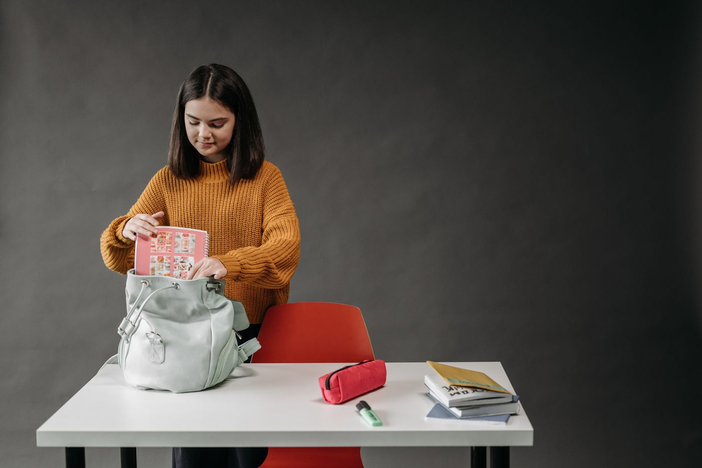 A student putting a notebook into a backpack