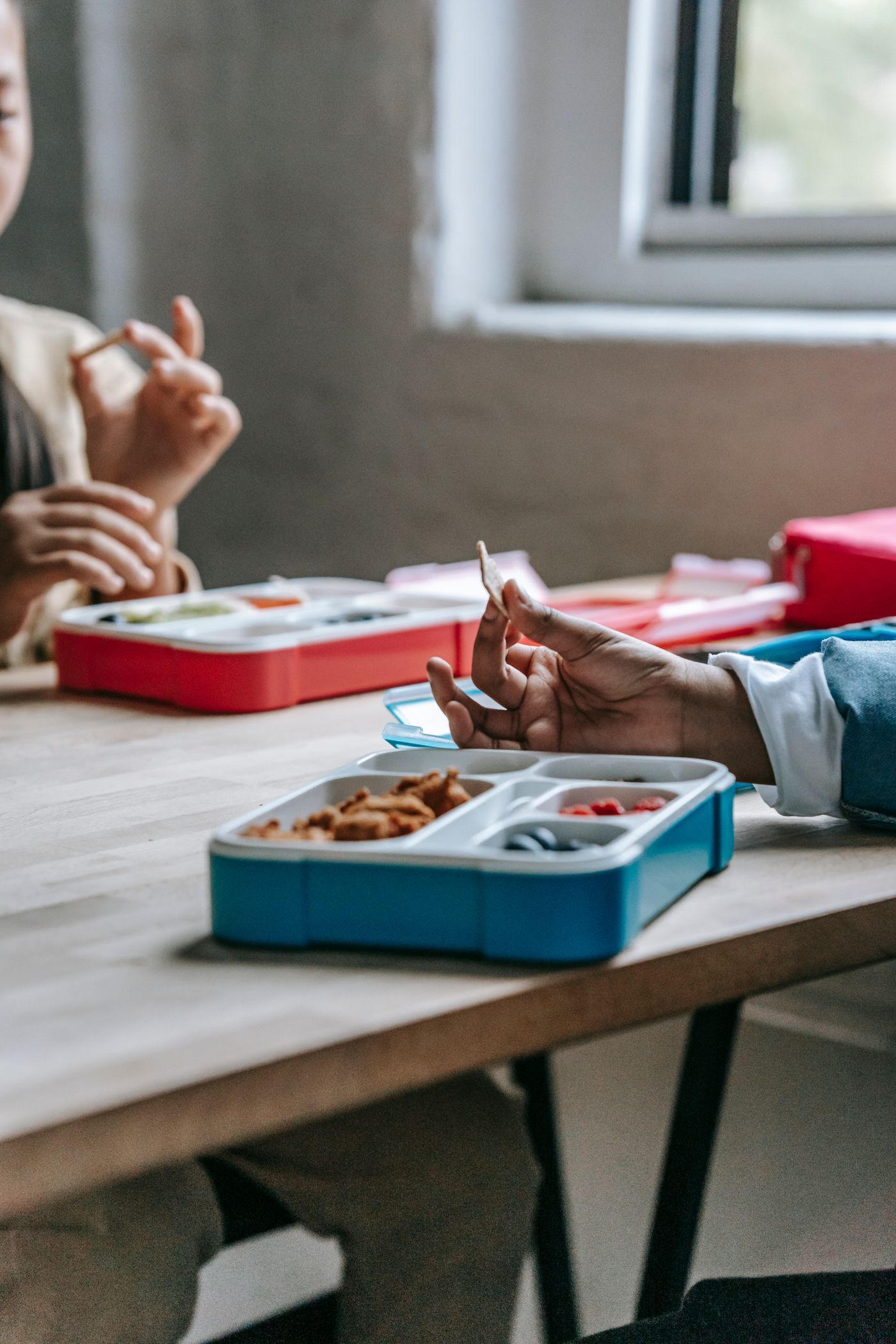 Children eating from lunch boxes at a table