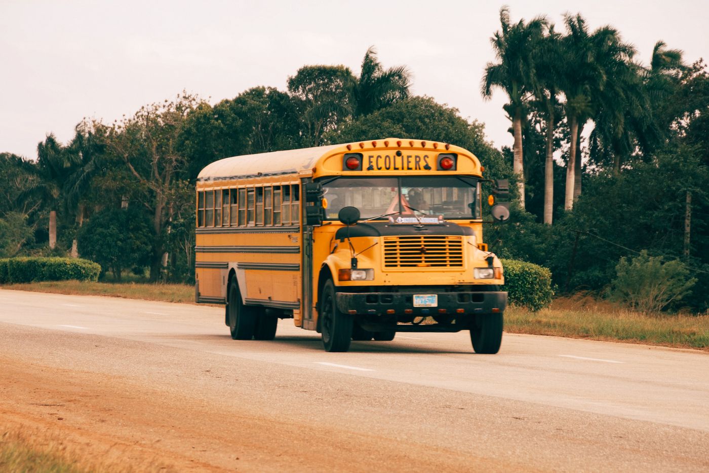 A yellow school bus travelling along a road