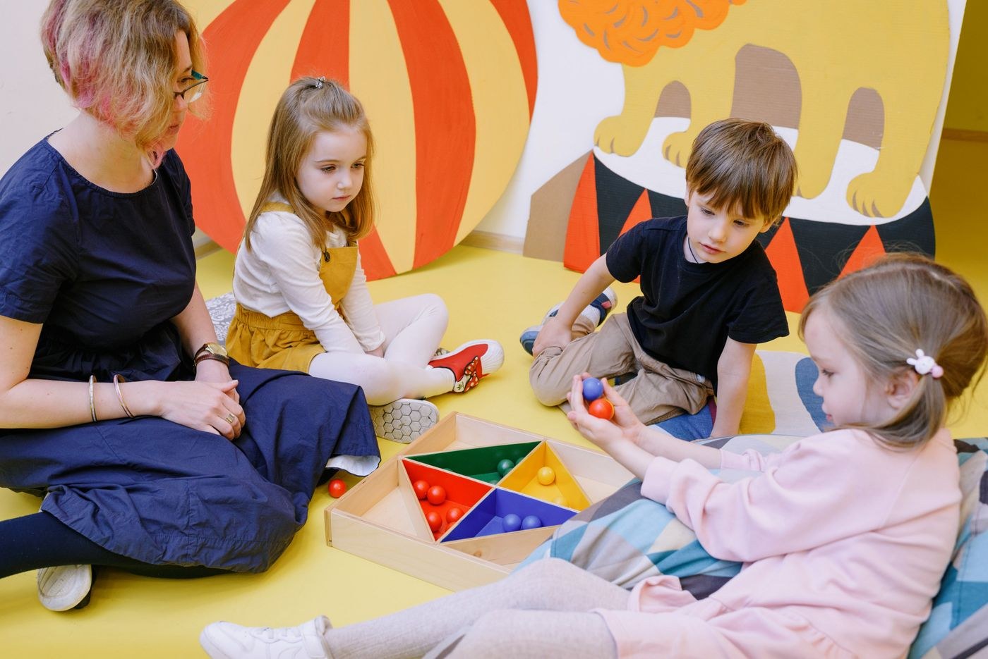 Children and an adult playing with geometric toys on the floor