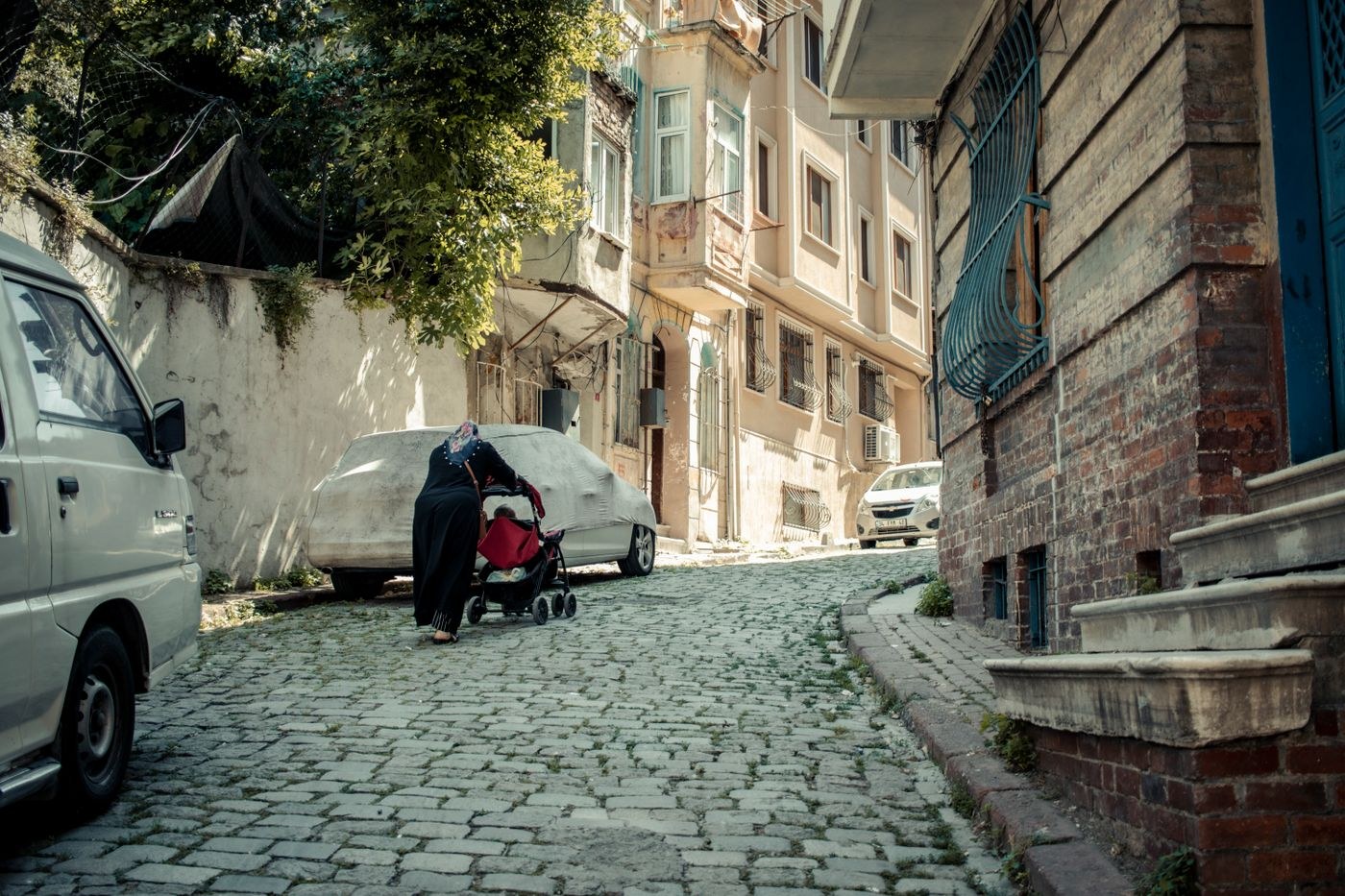 A woman pushing a stroller along a cobbled street