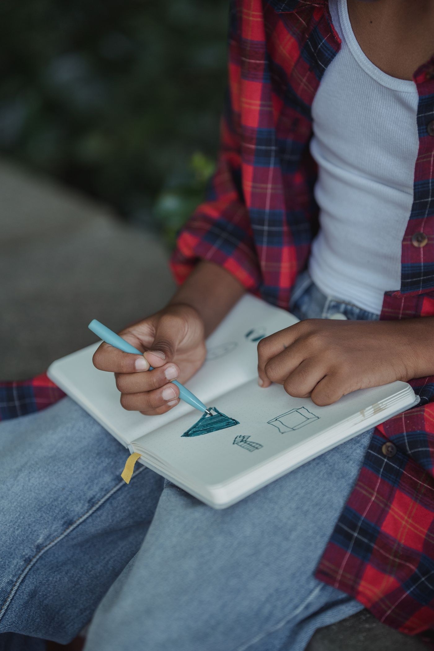 A child drawing in a notebook outdoors