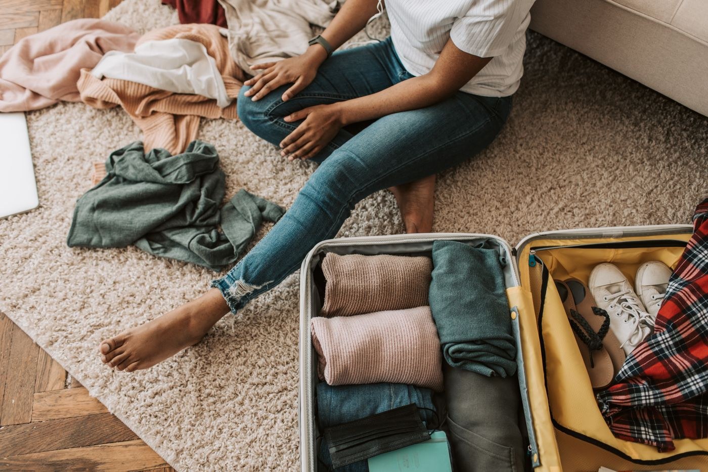 A woman arranging clothes beside an open suitcase