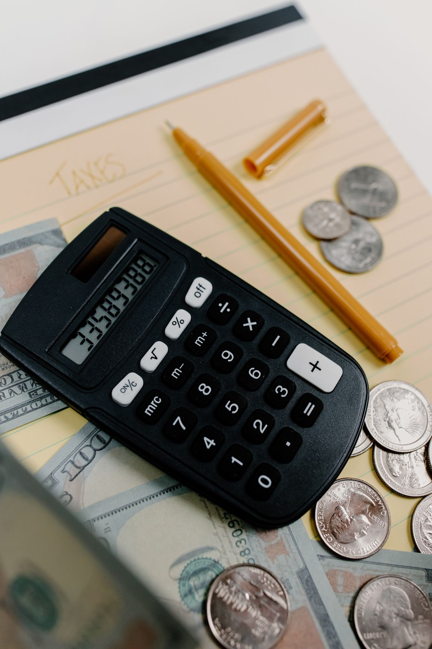 A calculator, notes and coins on a desk