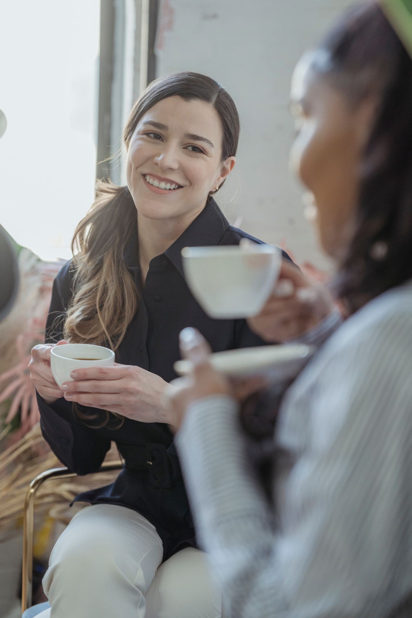 Two women talking with cups in their hands