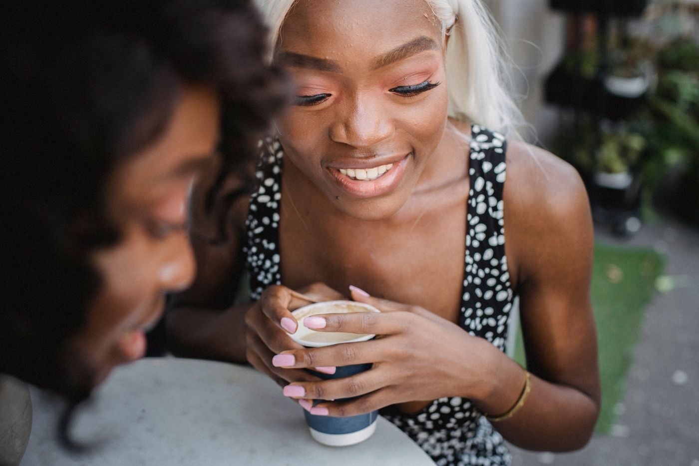 Two women talking across an outdoor cafe table