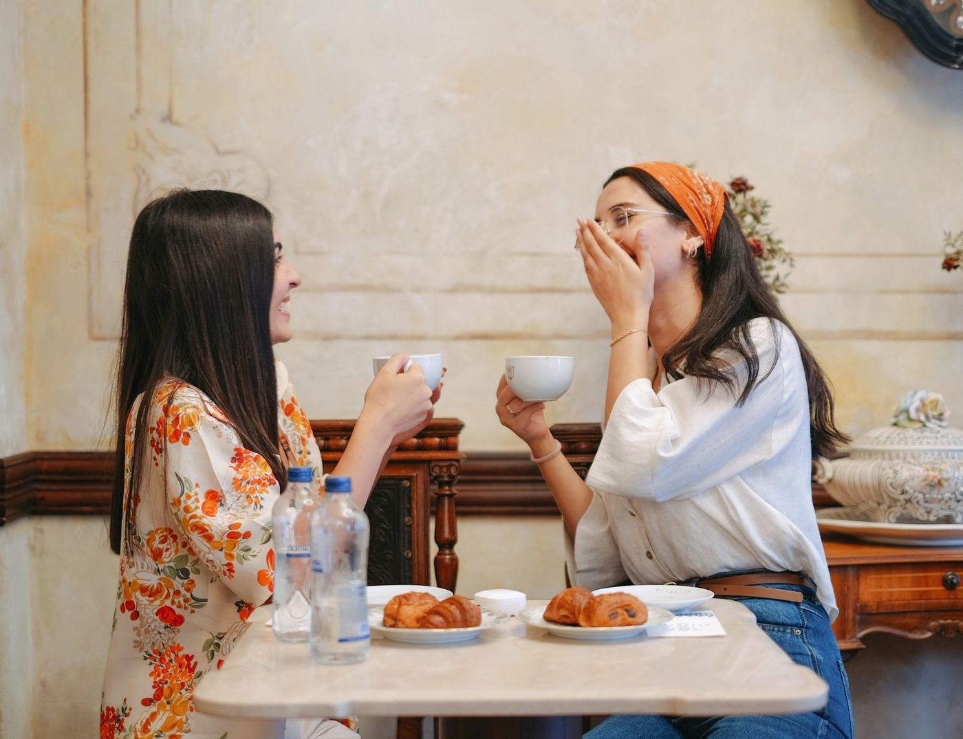 Two women sharing coffee and pastries at a cafe