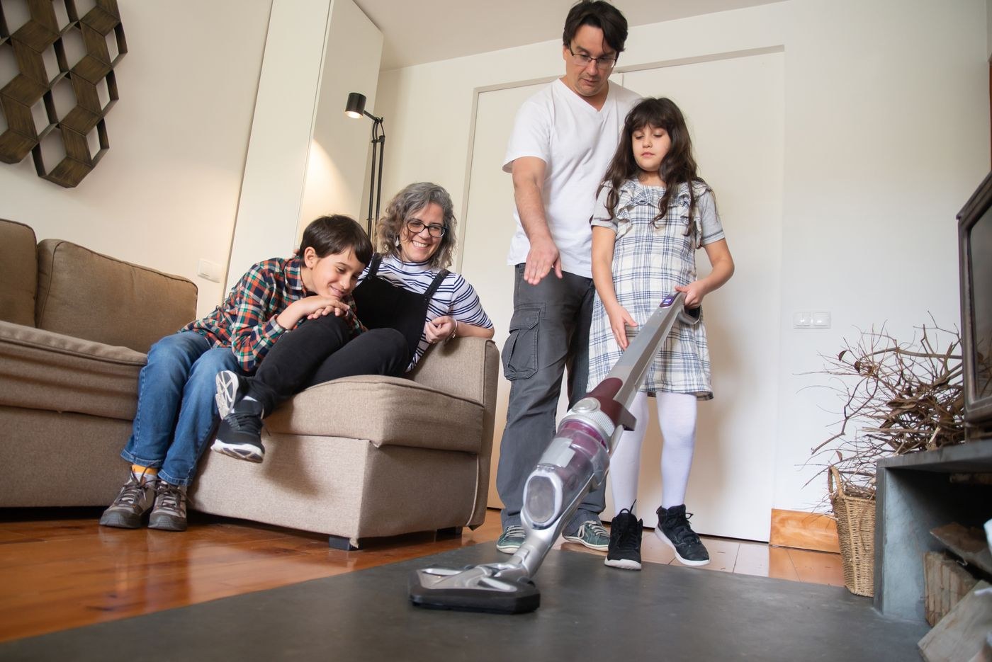 Adults and a child with a vacuum cleaner in a living room