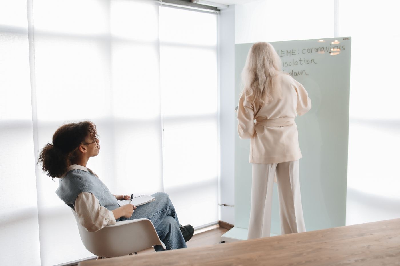 An adult teaching beside a whiteboard while another listens